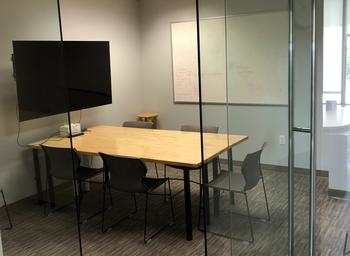 A small meeting room with table, chairs, and large TV screen.